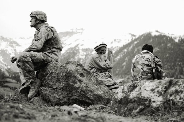 Soldaten sitzen mit einem alten Mann in den Bergen