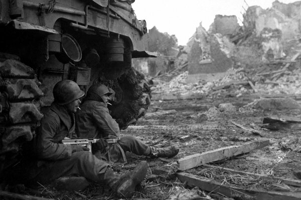 Soldaten sitzen in der Nähe eines Panzers mit einer Waffe in der Hand