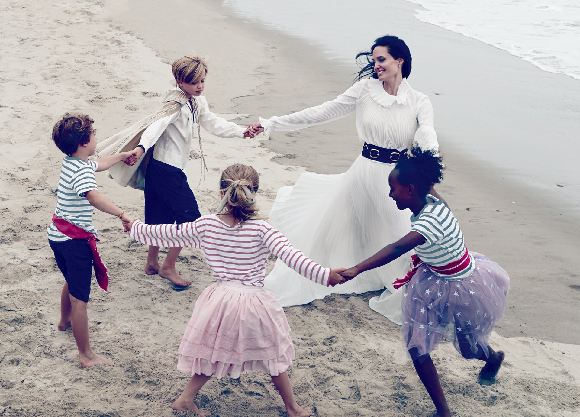 angelina jolie attrice bruna in bianco vestito bambini divertimento danza rotonda mare sabbia riva moda 2015 annie leibovitz