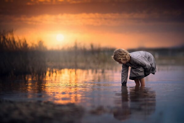 Das Mädchen beugte sich zum Wasser, in dem die Sonne reflektiert wurde