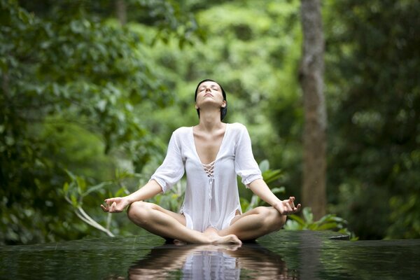 Mujer medita en la naturaleza en posición de loto