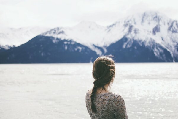 A girl in the wind against the background of mountains