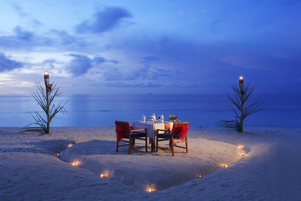 A set table with a romantic dinner in the evening on a deserted beach