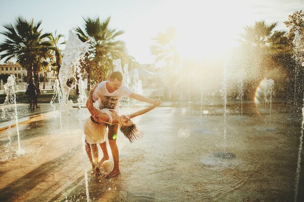 Amoureux dansant dans une fontaine sur fond de palmiers