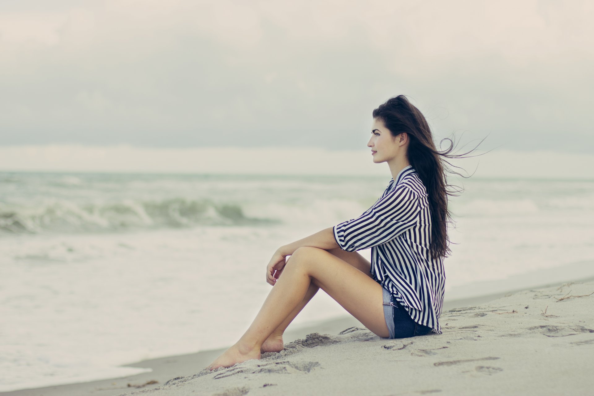 mädchen braunhaarig strand sand wind profil pose sitzen