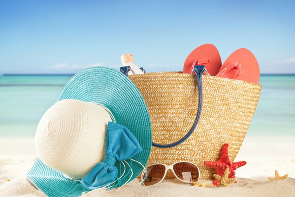 Beach bag and accessories on the sand by the sea