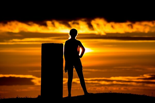 La silhouette de la jeune fille sur le coucher du soleil