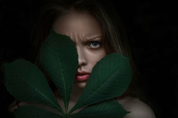 Portrait of a disgruntled girl with a leaf