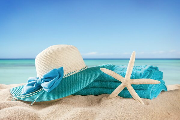 Cappello bianco e blu, asciugamano e Stella Marina sullo sfondo del mare
