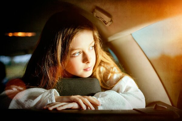 La jeune fille regarde par la fenêtre de la voiture