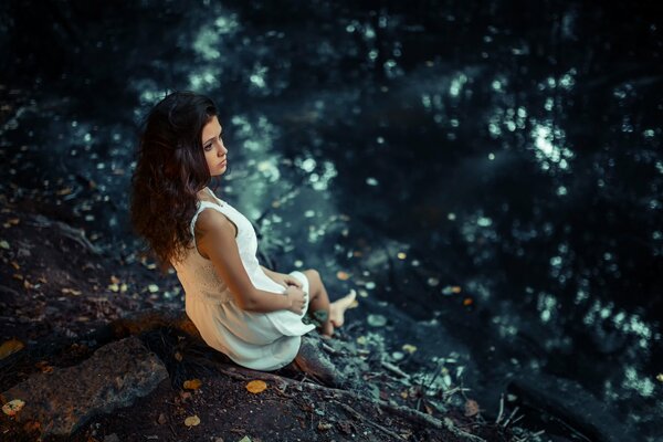 Brown-eyed Karina in a white dress on a rocky shore