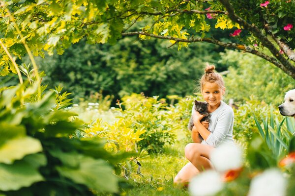 Ragazza con il gatto ed il cane sulla natura