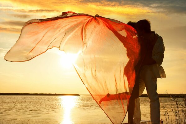 La jeune fille avec un gars rencontrent le coucher de soleil sur le lac