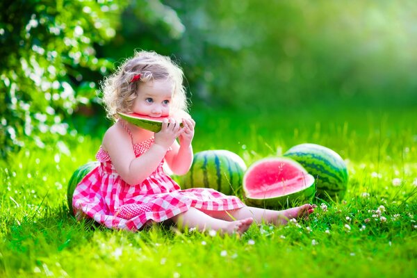 Fille en robe mange une pastèque sur la pelouse