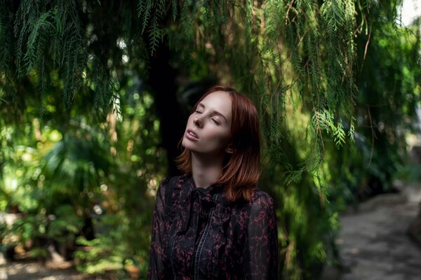 Mädchen mit geschlossenen Augen steht unter einem Baum