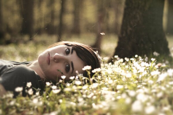 Chica en el bosque yace en las flores