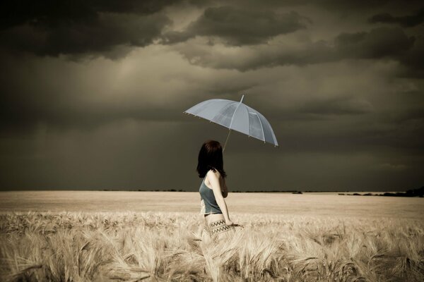 Chica con paraguas en el campo antes de la tormenta