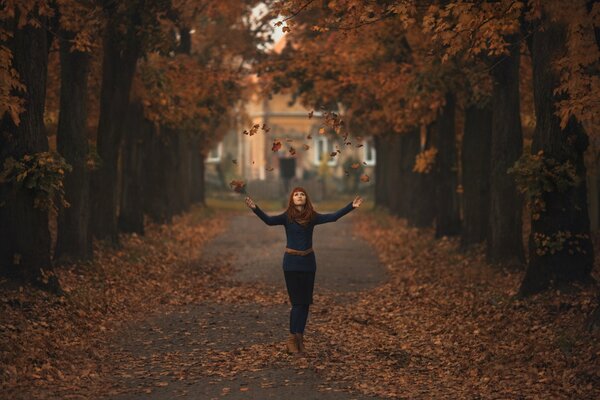 A girl on an autumn alley in the foliage