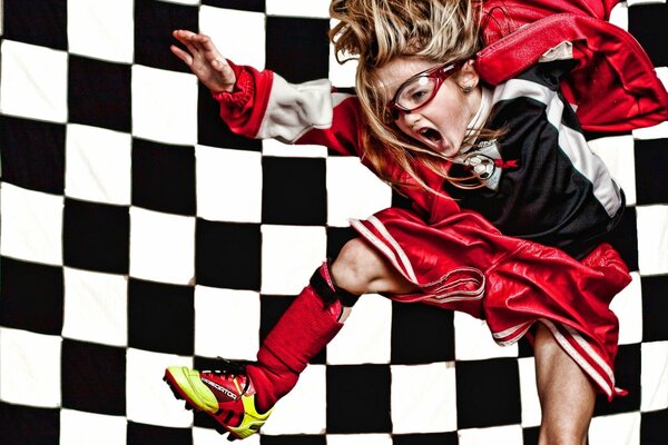 A girl in glasses and boots on a background of black and white squares