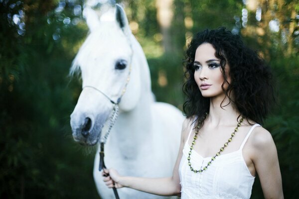 Bruna in abito bianco con cavallo bianco