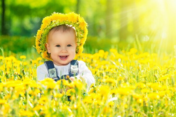 Happy baby on the background of sunny dandelions