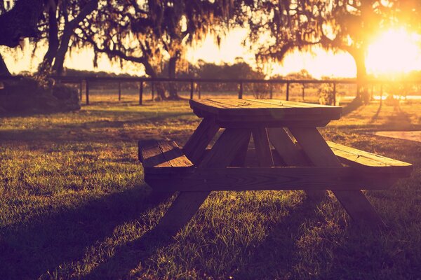 Banco de madera con mesa en el fondo de la puesta de sol