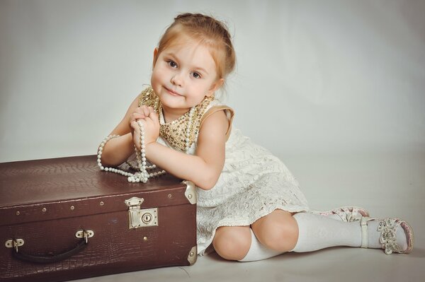 A little girl with beads and a suitcase