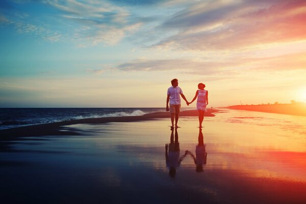Una pareja camina por la orilla del mar al atardecer