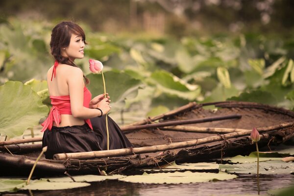 Ragazza che galleggia su una barca e tiene un fiore