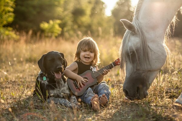 Bambino con la chitarra con gli amici cane e cavallo