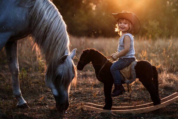 Horse eats grass boy sits on a toy horse