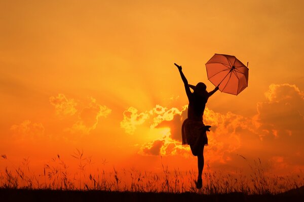Fille avec un parapluie dans les rayons du coucher du soleil
