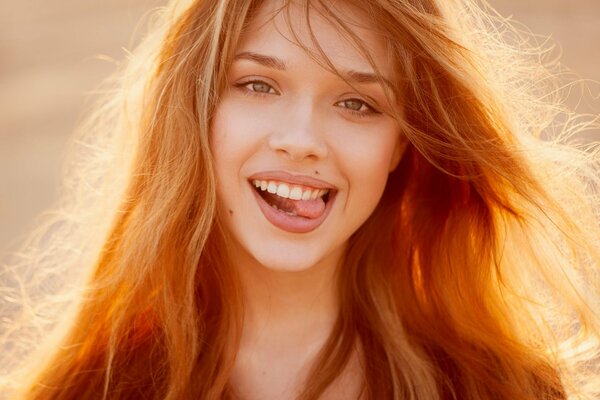 A beautiful red-haired girl smiles on a summer day