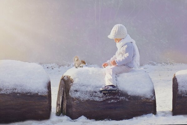 Il bambino nutre lo scoiattolo in inverno