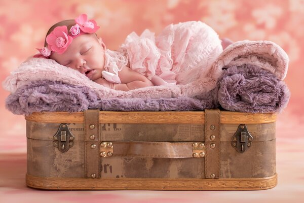 Un bambino con una corona in testa dorme su una valigia