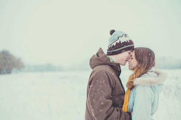 El chico y la chica se abrazan suavemente en medio de la nieve
