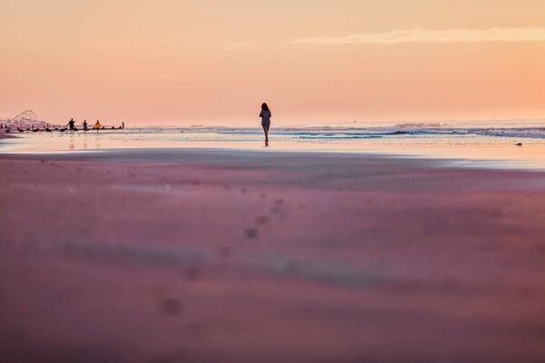 Silhouette of a girl on the sand near the sea