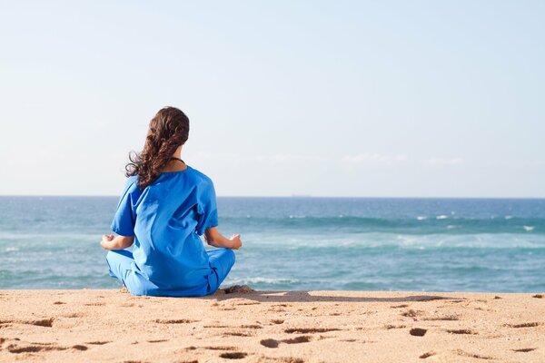 La jeune fille se détend de yoga au bord de la mer
