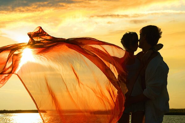 Couple câlins sur fond de coucher de soleil sur le lac