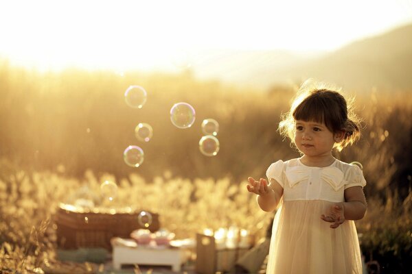 Girl playing with soap bubbles in summer