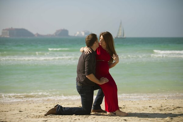 Jeune fille assise sur le genou de son jeune homme au bord de la mer
