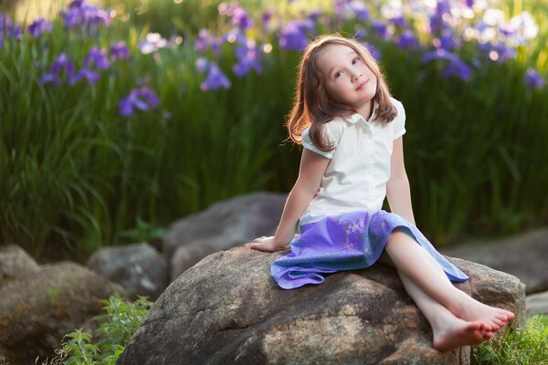 La fille sur la pierre dans le bleu de la jupe