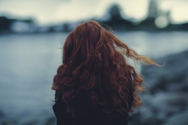 A red-haired girl stands in the wind