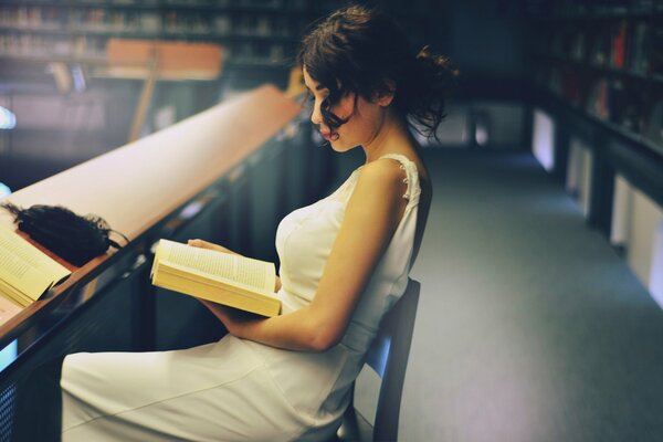 Hermosa chica leyendo un libro en la biblioteca