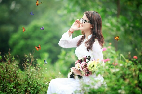 A girl with a bouquet of flowers at the edge of the forest