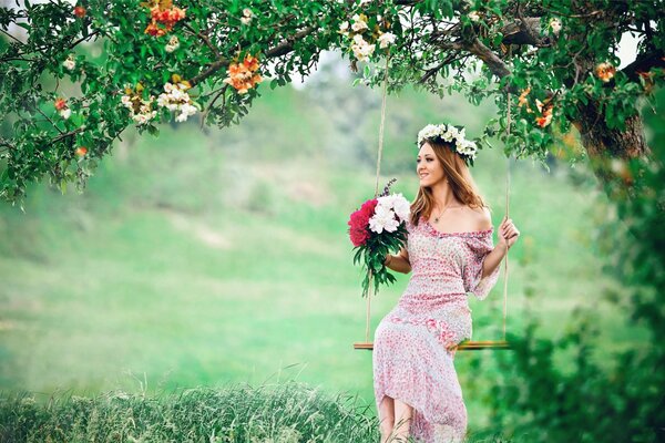 A girl on a swing in a summer forest