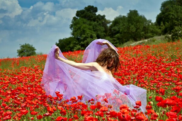 Mädchen im fliegenden Kleid auf der Wiese mit Mohnblumen