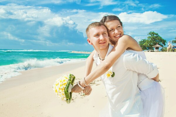 A couple in love on the white sand of the ocean with a daisy bouquet