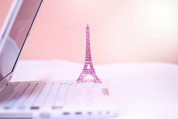 Estatuilla rosa de la torre Eiffel en una computadora portátil