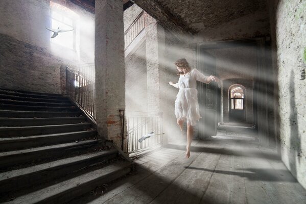 Una casa abandonada y una chica bailando con un vestido blanco